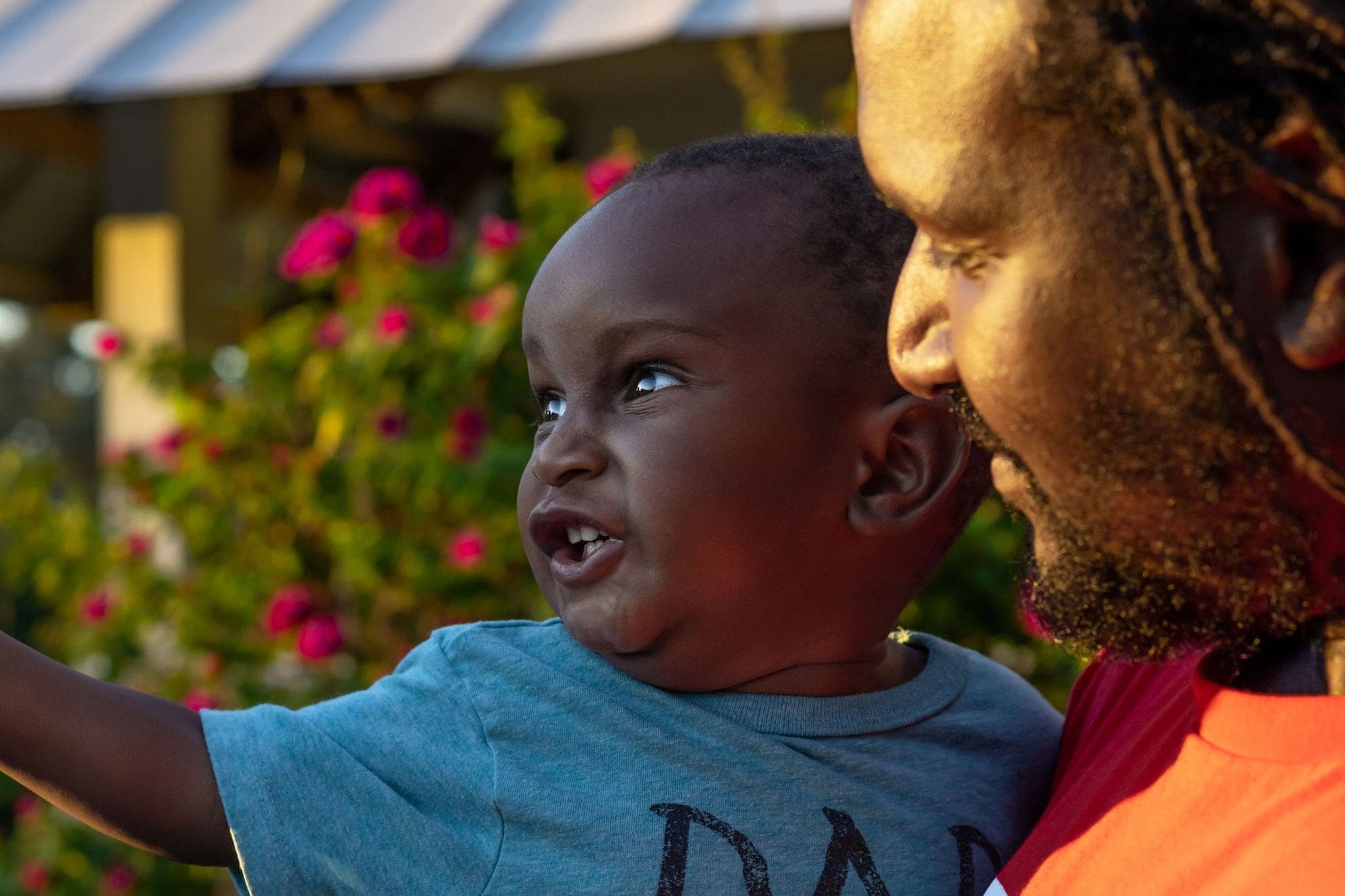 A father and his toddler son laughing among flowers