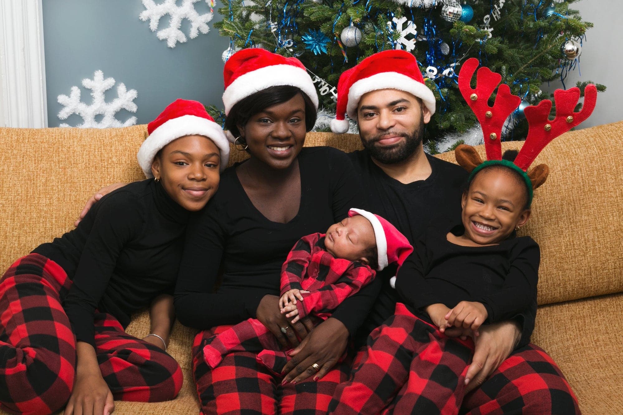 A family in matching pyjamas and Santa hats with their newborn