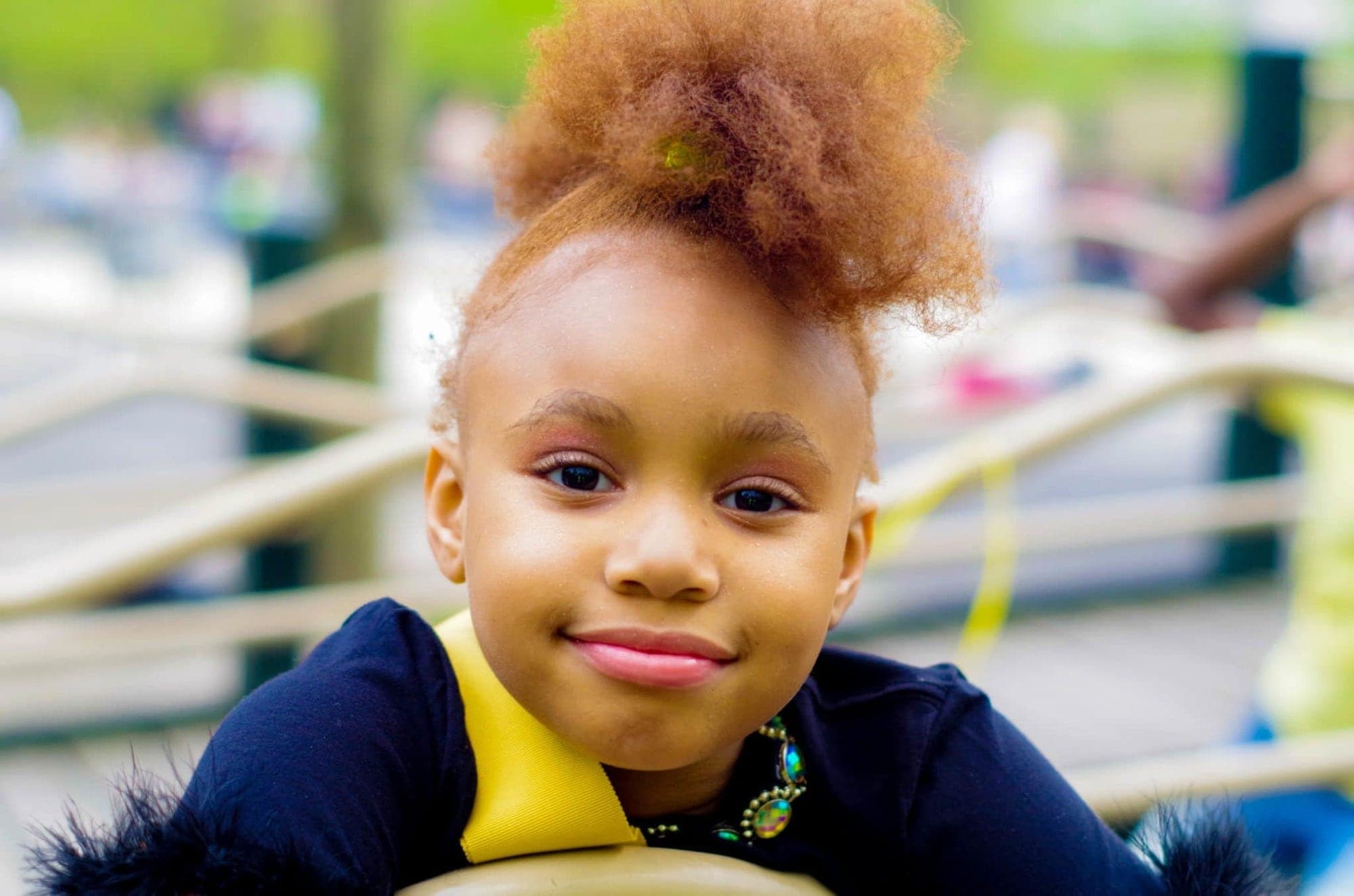 A smiling little girl with her hair up in a puff