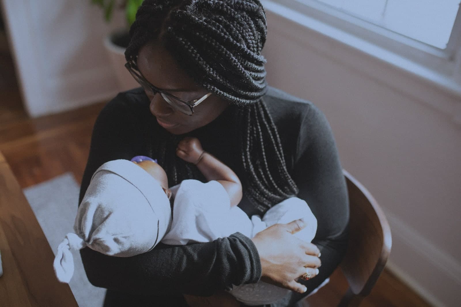Before: A mother gazing down at the newborn in her arms, in cold window light